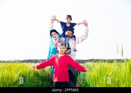 Portrait d'une famille de jeunes agriculteurs indiens heureux debout dans le champ de l'agriculture de blé, parents avec enfants en plein air, concept de l'inde rurale. Copier l'espace Banque D'Images