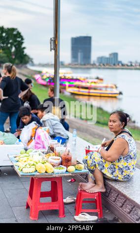 Phnom Penh, Cambodge-4 janvier 2023: Les vedors de nourriture attendent pour passer le commerce, tout en socialisant, comme le froid relatif de la journée arrive, après le coucher du soleil. Banque D'Images