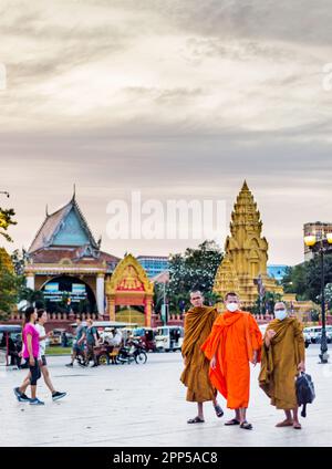 Phnom Penh,Cambodge-4 janvier 2023:les moines Khmers, portant des masques faciaux, marchent le long du quai piétonnier de Sisowath, en face du Palais Royal, au soleil Banque D'Images