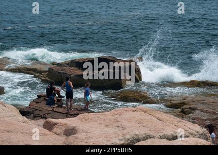 Famille regardant les vagues s'écraser sur la rive près de Thunder Hole dans le parc national Acadia Banque D'Images