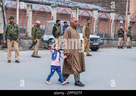 Srinagar, Inde. 22nd avril 2023. L'homme de Kashmiri avec son enfant passe devant des policiers indiens, debout sous la garde devant la Grande Mosquée fermée du Cachemire ou Jamia Masjid le jour d'Eid-al-Fitr. Pour l'année 4th consécutive, les autorités indiennes ont interdit aux personnes d'offrir des prières d'Eid à la Grande Mosquée historique du Cachemire, dans le centre-ville de Srinagar. Crédit : SOPA Images Limited/Alamy Live News Banque D'Images