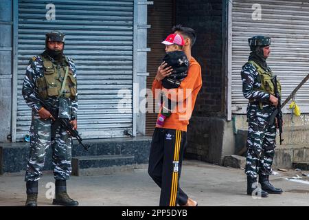 Srinagar, Inde. 22nd avril 2023. L'homme de Kashmiri et son fils se promèneront devant les troupes paramilitaires indiennes, debout sous la garde devant la Grande Mosquée fermée du Cachemire ou Jamia Masjid le jour d'Eid-Al-Fitr. Pour l'année 4th consécutive, les autorités indiennes ont interdit aux personnes d'offrir des prières d'Eid à la Grande Mosquée historique du Cachemire, dans le centre-ville de Srinagar. Crédit : SOPA Images Limited/Alamy Live News Banque D'Images