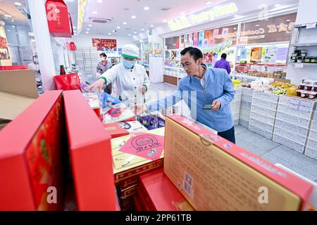 (230422) -- LANZHOU, 22 avril 2023 (Xinhua) -- Zhu Yanjun achète des pâtisseries, comme cadeaux pour ses collègues de sa ville natale, dans un magasin d'une marque traditionnelle chinoise de boulangerie à Pékin, capitale de la Chine, 12 avril 2023. Zhu Yanjun, 50 ans, est le finaliste du Concours chinois de poésie 2023. Après avoir obtenu son diplôme d'études secondaires en 1992, il a cessé ses études et a quitté sa ville natale, un village dans le comté de Jingning, dans la province de Gansu, dans le nord-ouest de la Chine, et a commencé à travailler comme travailleur migrant. Au cours des 30 dernières années, bien qu'il ait toujours été occupé à travailler pendant la journée, il a continué à dépenser sa réserve Banque D'Images