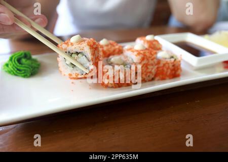Personne prend des sushis avec des baguettes au restaurant Banque D'Images