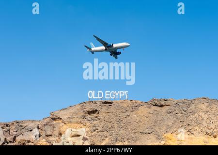 Panneau VIEILLE ÉGYPTE sur les rochers sur fond de ciel avec avion. Destination du voyage. Banque D'Images