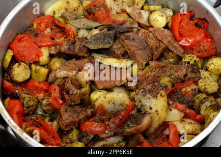 Un plateau de tranches de pommes de terre, oignon, tomate, poivron coloré, morceaux de viande, épices, ail et paprika, foyer sélectif de pommes de terre avec viande de boeuf et légumes Banque D'Images