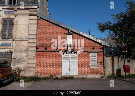 Façade d'une ancienne petite maison en brique rouge avec volets en bois blanc Banque D'Images