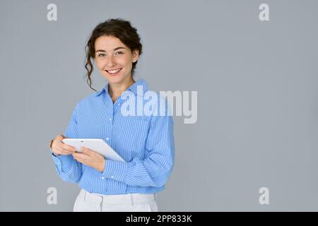 Jeune femme d'affaires professionnelle heureuse utilisant une tablette numérique isolée au gris. Banque D'Images