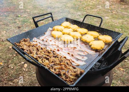 Hamburgers, fromage, bacon, oignons et champignons, friture sur un barbecue. Personne Banque D'Images