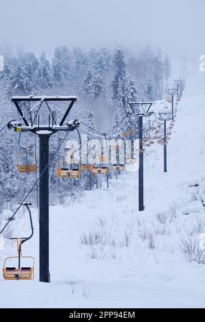 Station de ski d'hiver Teletsky Altai près d'Iogach. Ascenseur sur le mont et sur fond de forêt sous les chutes de neige. Banque D'Images