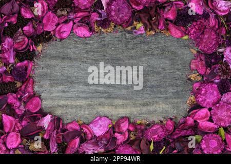 Cadre de bordure, vue de dessus de potpourri principalement rose avec des cônes de pin et des boutons de fleur de couleur foncée, sur un centre en bois rustique dans un éclairage doux Banque D'Images