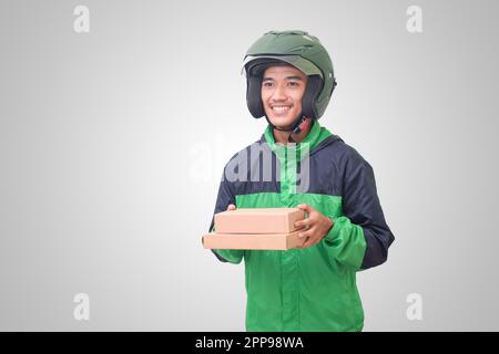 Portrait d'un pilote de messagerie en ligne asiatique portant une veste et un casque verts et livrant le colis et la boîte pour le client. Image isolée sur fond blanc Banque D'Images