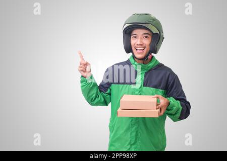 Portrait d'un pilote de messagerie en ligne asiatique portant une veste et un casque verts et livrant le colis et la boîte pour le client. Image isolée sur fond blanc Banque D'Images