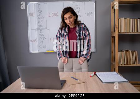 Étudier l'anglais en ligne. Professeur sérieux de langue étrangère sur le Web à l'aide d'un ordinateur portable. Le formateur explique les règles de grammaire aux étudiants sur Banque D'Images