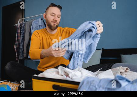 Homme emballant la valise pour le voyage dans la chambre. Concept de voyage. Banque D'Images