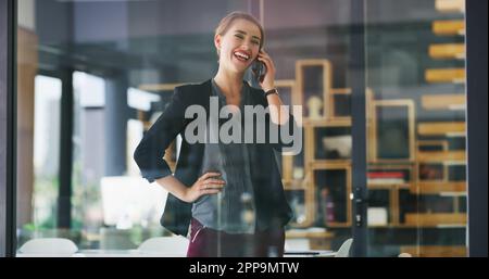 Conclure la vente par téléphone. une jeune femme d'affaires attirante debout seule dans son bureau et parlant sur son téléphone portable. Banque D'Images