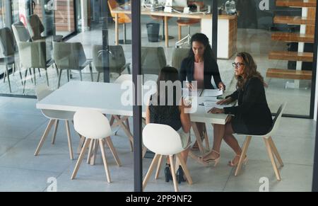 La salle de réunion est le point de départ des affaires. Prise de vue en grand angle de trois jeunes femmes d'affaires assises dans la salle de réunion lors d'une réunion de direction. Banque D'Images