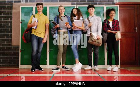 Tout le monde est ravi de passer le test avec. Portrait d'un groupe de jeunes enfants gaies qui parlent entre eux avant la classe à l'intérieur d'une école Banque D'Images