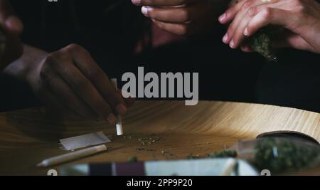 Consommer des rouleaux de cannabis. des hommes qui roulent un joint de marijuana à la maison. Banque D'Images