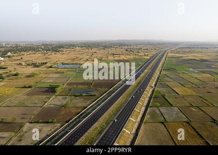 tir de drone aérien à trépied verrouillé de new delhi mumbai jaipur express autoroute surélevée montrant six voies de route avec des feids verts avec des fermes rectangulaires Banque D'Images