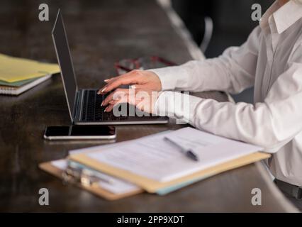 Prise de vue rognée de la dame à l'aide de la saisie sur ordinateur portable sur le clavier à l'intérieur Banque D'Images