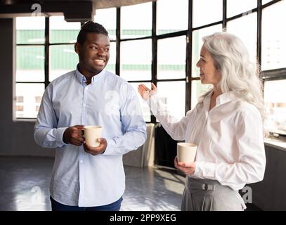 Divers collègues couple ayant une pause-café debout dans le bureau moderne Banque D'Images