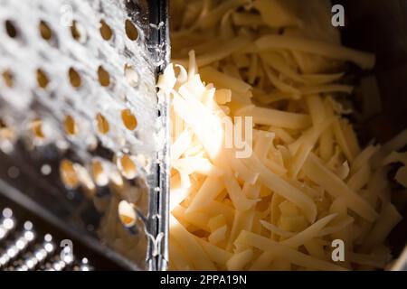 Fromage râpé jaune, matière fondue, râpe à fromage. Banque D'Images