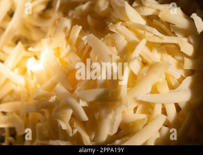 Fromage râpé jaune, matière fondue, râpe à fromage. Banque D'Images