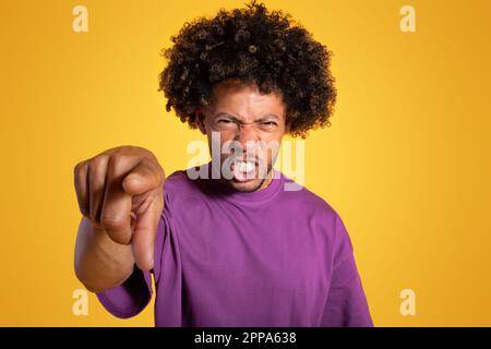 Un homme mauri afro-américain adulte triste en colère, en t-shirt violet, pointant le doigt vers l'appareil photo Banque D'Images