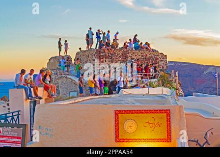 Bougainvilliers et Château d'Oia surpeuplé au coucher du soleil. Touristes appréciant la vue sur le coucher du soleil. Vue sur la mer depuis la tour de guet survivante.Santorini,2013 Banque D'Images