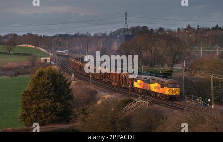 Colas Railfreight classe 56 locomotives 56094 + 56090 transportant un long train de marchandises transportant du bois sur la ligne principale de la côte ouest Banque D'Images