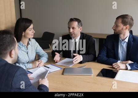 Homme d'affaires mature et confiant, patron parlant à des employés plus jeunes Banque D'Images