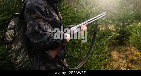 Chasseur avec un fusil et un sac à dos dans la forêt. Photo de haute qualité Banque D'Images