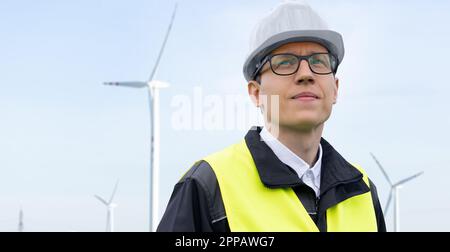 Portrait d'un ingénieur dans un casque et des lunettes sur un fond d'éoliennes. Photo de haute qualité Banque D'Images