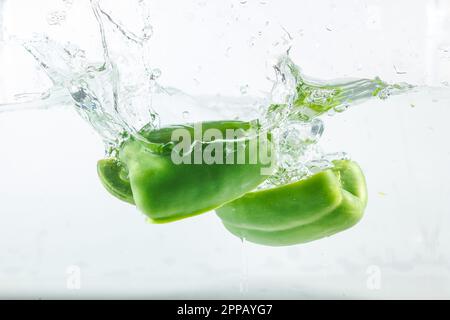 Poivre doux dans les éclaboussures d'eau, poivron vert sur fond blanc.Les poivrons doux sont un type de poivre.Pas épicé Banque D'Images