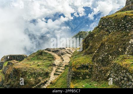 Partie de la route de l'Inca de Cusco à Machu Picchu avec des nuages entourant les montagnes et le chemin clair établi pour les randonneurs Banque D'Images