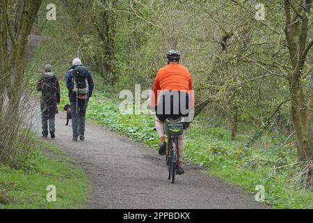 Un cycliste sur le point de passer deux randonneurs et un chien sur le Sett Valley Trail dans le Derbyshire Banque D'Images