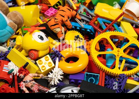 Une abondance de jouets dans la chambre des enfants, beaucoup de pièces en plastique multicolores de designers, pièces de rechange pour jouets, figurines et cubes. Banque D'Images