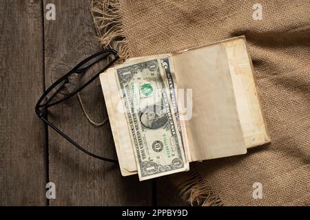 les dollars américains se trouvent sur un vieux livre sur une table en bois sur le virement de bord, de l'argent pour l'éducation Banque D'Images