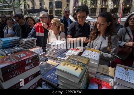 Barcelone, Espagne. 23rd avril 2023. Un groupe de personnes examine les livres affichés dans l'un des stands de la Rambla. La Catalogne célèbre chaque année le jour de Sant Jordi sur 23 avril, le festival traditionnel du livre et de la rose. Les rues sont pleines d'étals vendant des livres et des roses. Crédit : SOPA Images Limited/Alamy Live News Banque D'Images