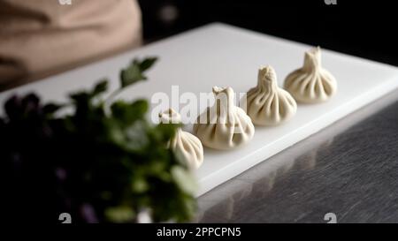 Cuisine géorgienne, khinkali. Khinkali a préparé de la viande crue et de la pâte, au plat national géorgien. Sculpter de grands khinkali. Banque D'Images