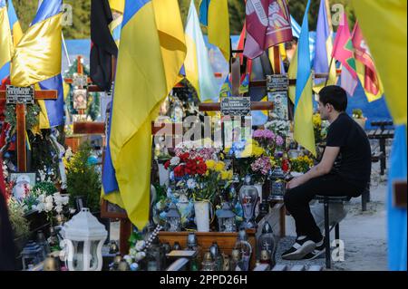 Lviv, Ukraine 23 avril 2023. Les gens se tiennent à des tombes dans le champ de Mars au cimetière de Lychakiv. Héros de l'Ukraine, les militaires qui ont défendu le territoire de l'Ukraine sont enterrés ici. La Russie a envahi l'Ukraine le 24 février 2022, déclenchant la plus grande attaque militaire en Europe depuis la Seconde Guerre mondiale Banque D'Images