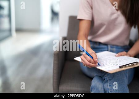 Femme avec stylo remplissant la forme assis dans la salle d'attente Banque D'Images