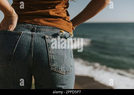 Fleurs dans la poche arrière du Jean porté par une femme à la plage Banque D'Images