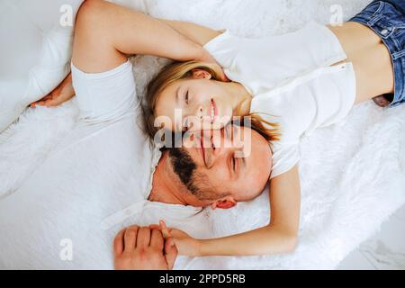 Fille souriante couchée avec son père au lit à la maison Banque D'Images