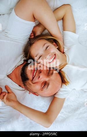 Homme souriant couché avec sa fille sur le lit à la maison Banque D'Images