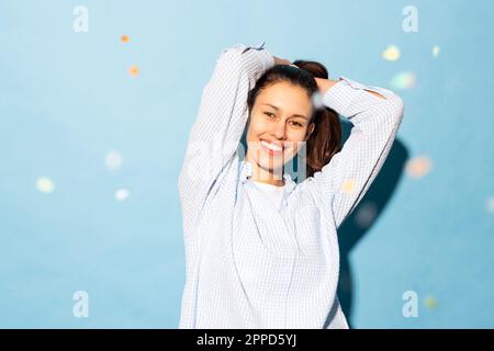 Jeune femme heureuse debout avec les bras levés sur fond bleu Banque D'Images