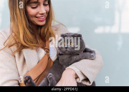 Bonne femme portant un sac à bandoulière tenant un chat Banque D'Images