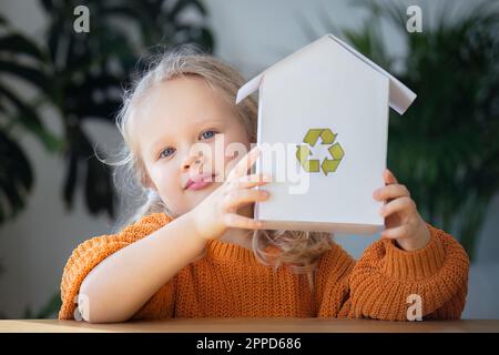 Fille tenant modèle de maison avec le logo de recyclage Banque D'Images