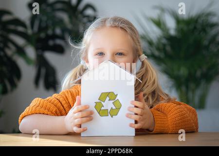 Blonde fille tenant modèle de maison avec logo de recyclage Banque D'Images